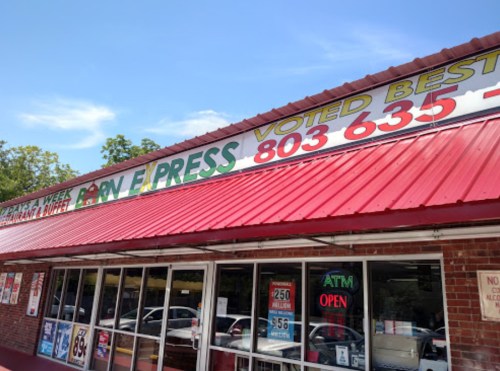 Exterior of a restaurant with a red roof, large colorful sign, and windows displaying "Voted Best" and "Open" signs.