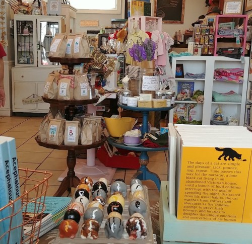 A cozy shop interior filled with colorful displays, gifts, and handmade items, including decorative eggs and bags.