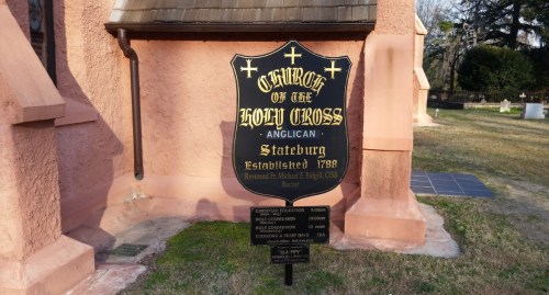 Sign for the Church of the Holy Cross, Anglican, established 1788, located in Stateburg, with service times listed.