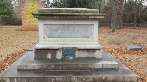 A stone monument dedicated to Thomas Sumter, surrounded by trees and fallen leaves in a quiet outdoor setting.