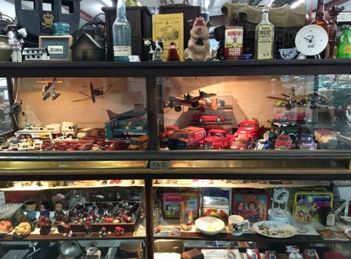 A display case filled with vintage toys, model cars, and various collectibles, showcasing a nostalgic assortment.