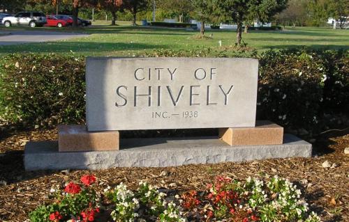 Sign for the City of Shively, established in 1938, surrounded by flowers and greenery.