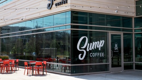 Exterior of Sump Coffee with large windows, featuring red outdoor seating and a prominent sign.