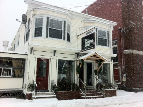 A two-story building with large windows, a sign reading "The Downtown Gallery," surrounded by snow during a snowfall.