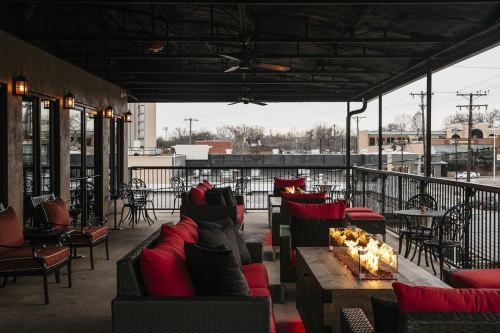 Cozy outdoor seating area with red cushions, fire pits, and a view of the city skyline on a cloudy day.