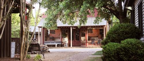 A quaint street scene featuring a building adorned with American flags, surrounded by greenery and rustic benches.