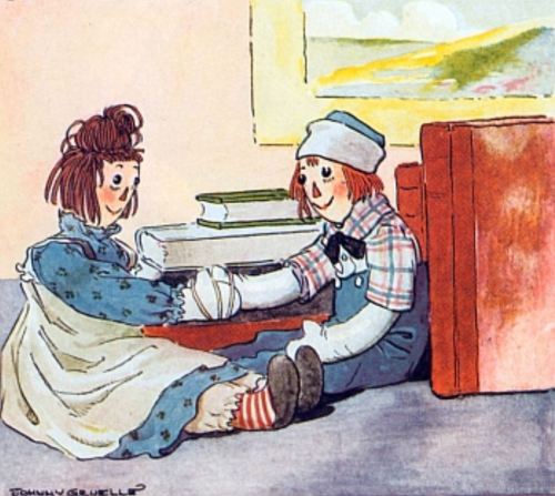 Two rag dolls sit on the floor, one bandaging the other's arm, surrounded by books and a cozy room setting.