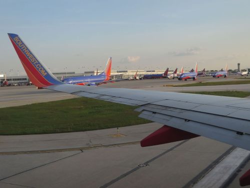 View from an airplane window showing a Southwest Airlines wing and several parked aircraft on the tarmac.