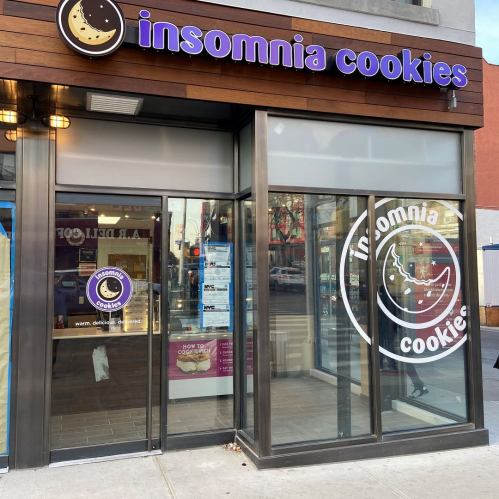 Exterior of Insomnia Cookies store with large windows and a sign featuring a moon and cookie logo.