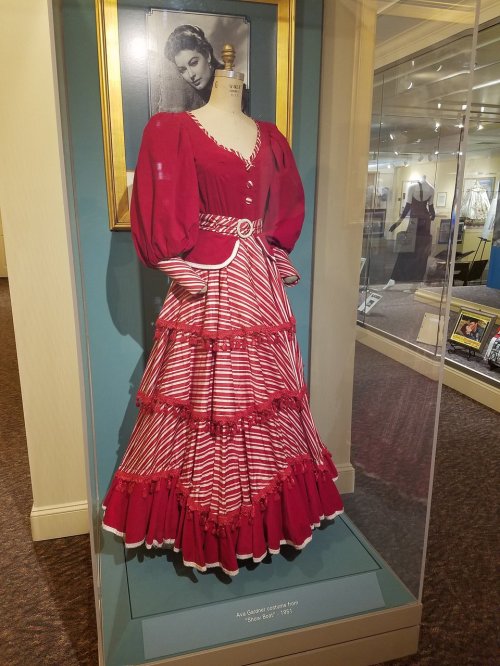 A vintage red and white striped dress displayed on a mannequin in a museum setting.