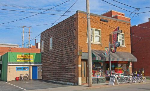 A brick building with a colorful storefront and bicycles outside, next to a green building under a blue sky.