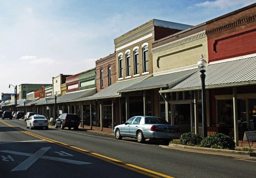 A charming street lined with historic buildings and parked cars under a clear blue sky.