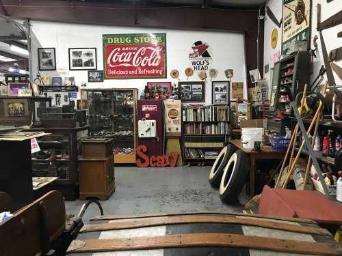 A vintage store filled with memorabilia, including Coca-Cola signs, old books, and antique items.