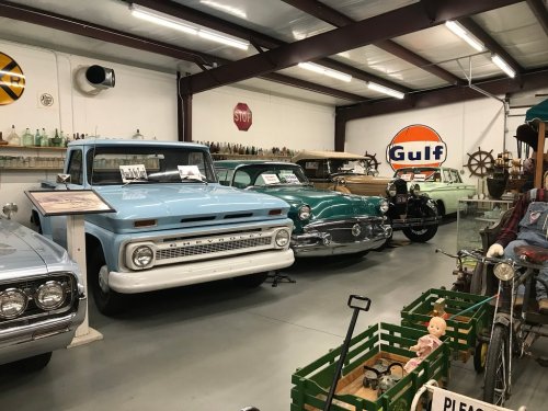 A collection of vintage cars displayed in a museum, featuring a blue Chevrolet truck and various classic models.