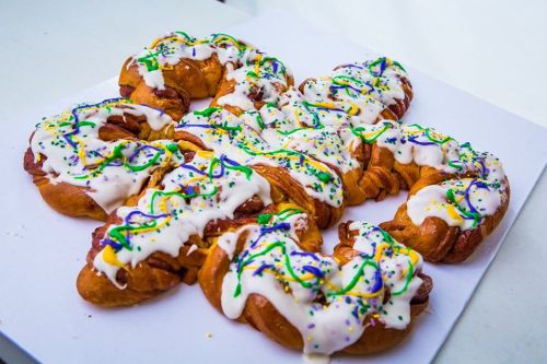 A colorful pastry topped with white icing and sprinkles, arranged in a decorative pattern on a white background.