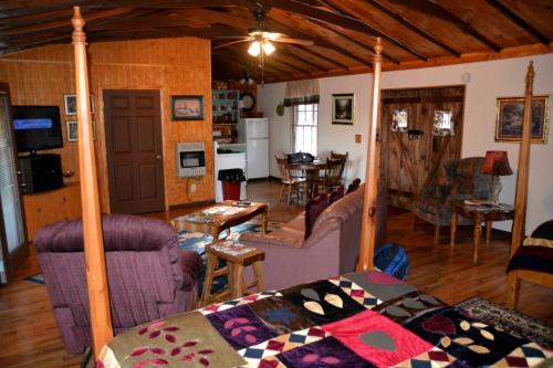 Cozy cabin interior featuring a four-poster bed, seating area, dining table, and rustic decor.
