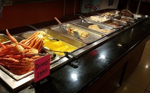 A buffet with various dishes, including crab legs, seafood, and baked items, labeled as "Dinner Item."