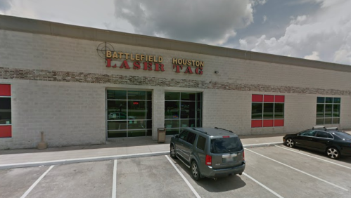 Exterior of Battlefield Houston Laser Tag building with parked cars and a cloudy sky.