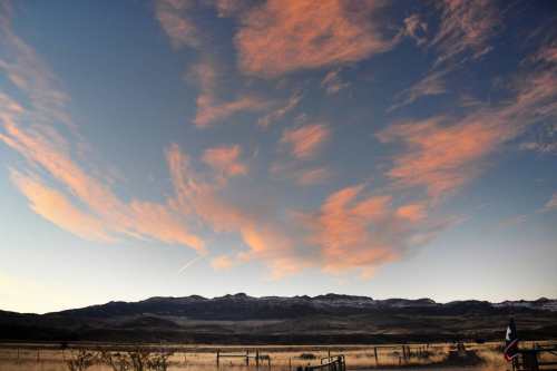 A scenic view of mountains under a sky filled with pink and orange clouds at sunset.