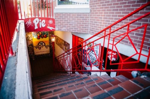 Staircase leading down to "The Pie" entrance, featuring red railings and brick walls adorned with colorful murals.