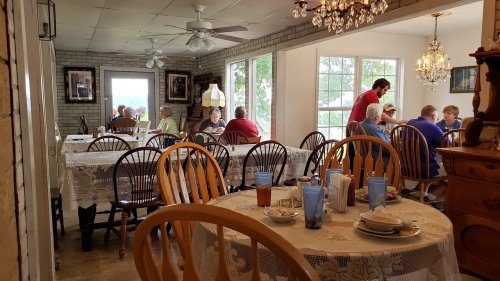 A cozy restaurant interior with tables set for dining, patrons enjoying meals, and a bright, welcoming atmosphere.