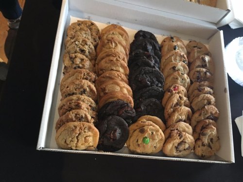 A box filled with an assortment of cookies, including chocolate chip and dark chocolate varieties, neatly arranged.
