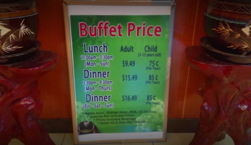 Sign displaying buffet prices for lunch and dinner, including adult and child rates, with discounts for seniors.