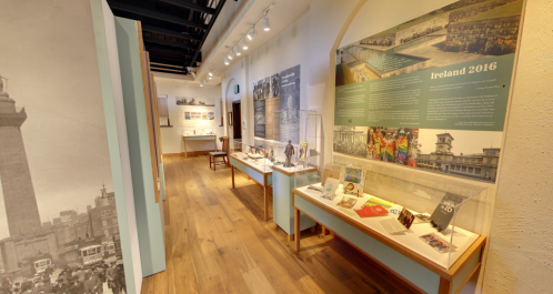 A museum interior featuring displays about Ireland 2016, with artifacts and informational panels along a wooden floor.