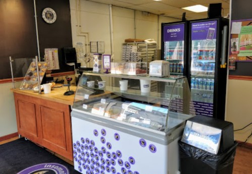 Interior of a dessert shop featuring a display case, drink fridge, and a counter with various treats.