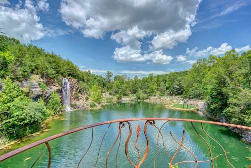A scenic view of a lush green landscape with a waterfall and a tranquil lake, framed by a decorative railing.