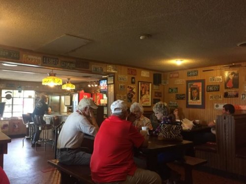 A cozy restaurant interior with patrons at tables, vintage posters on the walls, and warm lighting.