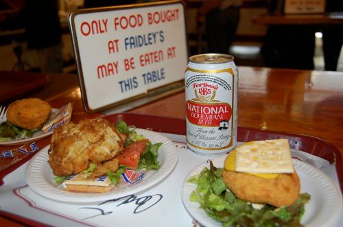 A tray with fried food, a beer can, and a sign stating only food bought at Faidley's may be eaten at this table.