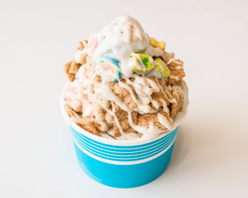 A colorful dessert cup filled with cereal, marshmallows, and drizzled with creamy frosting.