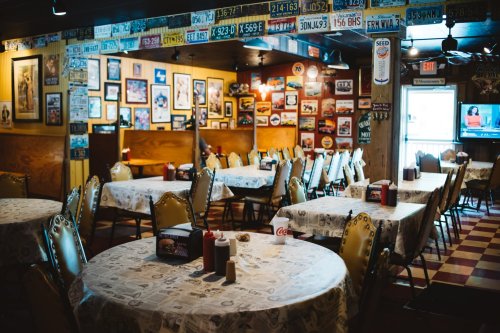 A cozy restaurant interior with tables, chairs, and walls adorned with vintage signs and memorabilia.