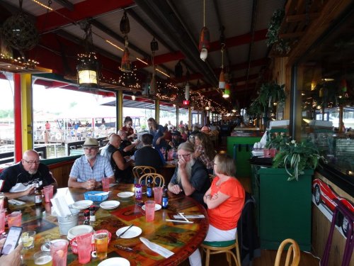 A lively restaurant scene with diners at colorful tables, enjoying food and drinks in a vibrant, decorated space.