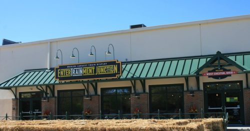 Exterior of EnterTRAINment Junction in West Chester, Ohio, featuring a green roof and hay bales in front.