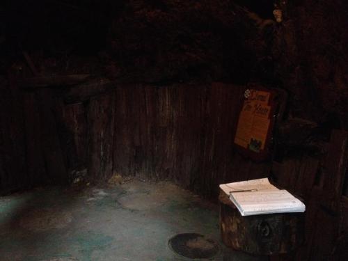A dimly lit wooden room with a sign on the wall and an open book on a wooden stump.