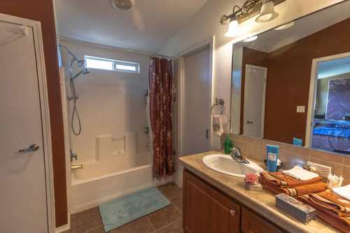 A bathroom featuring a shower, bathtub, sink with towels, and a mirror, with warm lighting and neutral decor.
