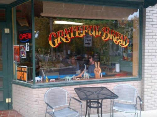A café window displays "Grateful Bread" with colorful signage, featuring outdoor seating and a cozy interior.
