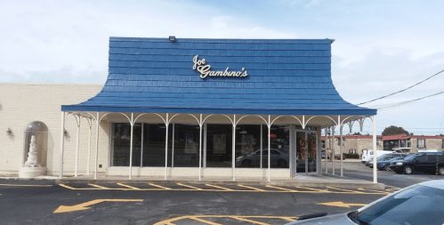Exterior of Joe Gambino's restaurant featuring a blue roof and large windows, with a parking lot in front.