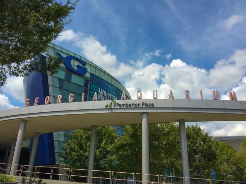 Exterior of the Georgia Aquarium building with blue skies and clouds in the background.