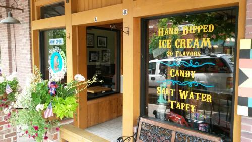 A storefront with a sign advertising hand-dipped ice cream, 20 flavors, candy, and saltwater taffy. Flowers in the foreground.