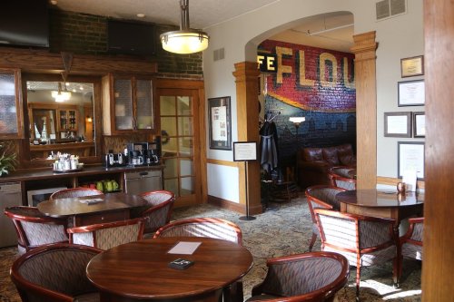 Cozy café interior with wooden tables, chairs, and a colorful mural on the wall, featuring a relaxed seating area.