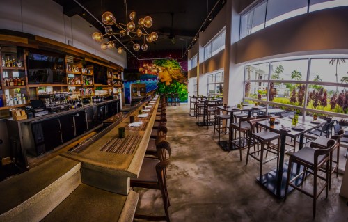 Modern restaurant interior featuring a bar, stylish seating, and a vibrant mural on the wall. Bright and spacious atmosphere.