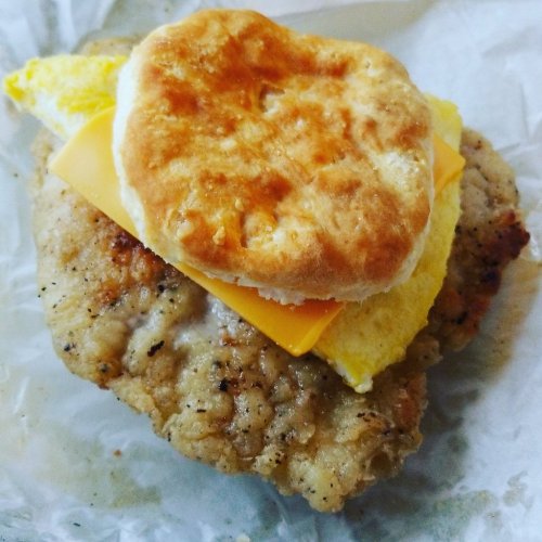 A crispy chicken patty topped with a fluffy biscuit, melted cheese, and a folded egg.