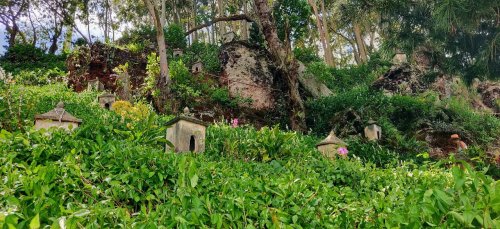 A lush green landscape with small stone structures nestled among trees and plants, creating a serene atmosphere.