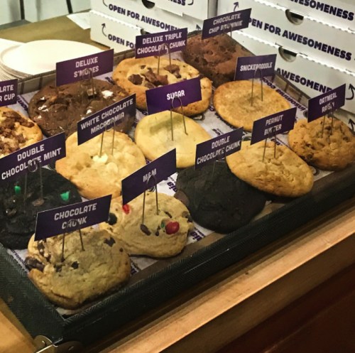 A display of various cookies with labels, including flavors like chocolate chip, peanut butter, and snickerdoodle.