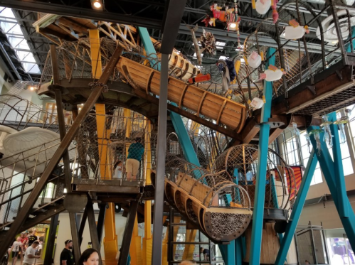 A colorful indoor play structure with slides, climbing areas, and children exploring various levels.