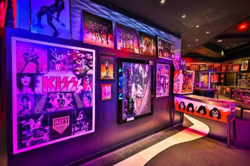 A vibrant display of KISS memorabilia, featuring colorful posters and artwork in a dimly lit gallery.