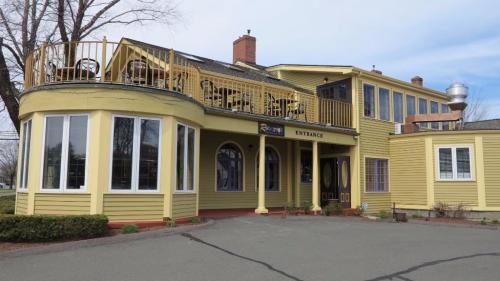 A yellow building with large windows, a welcoming entrance, and a balcony on the second floor.